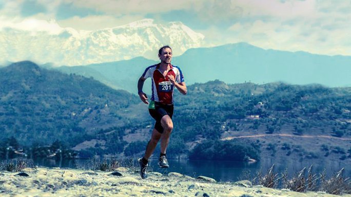 Triathlon participant running along Lake Begnas, surrounded by Himalayas, during Himalayan Rush, Pokhara, Nepal. 