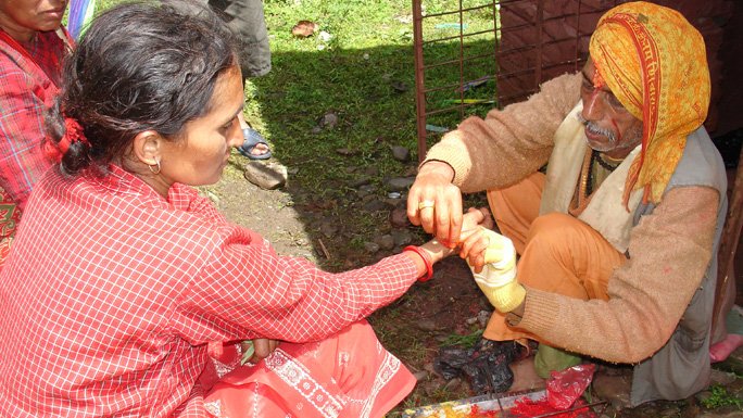 A Brahmin tying sacred thread or doro on a Hindu lady during Janai Purnima. 